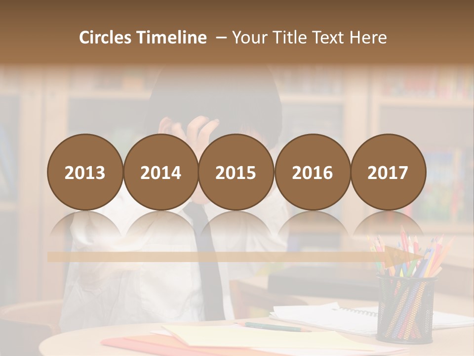 A Young Boy Sitting At A Desk In Front Of A Book Shelf PowerPoint Template