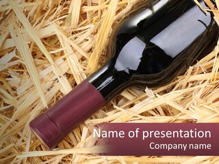 A Bottle Of Wine Sitting On Top Of Straw PowerPoint Template