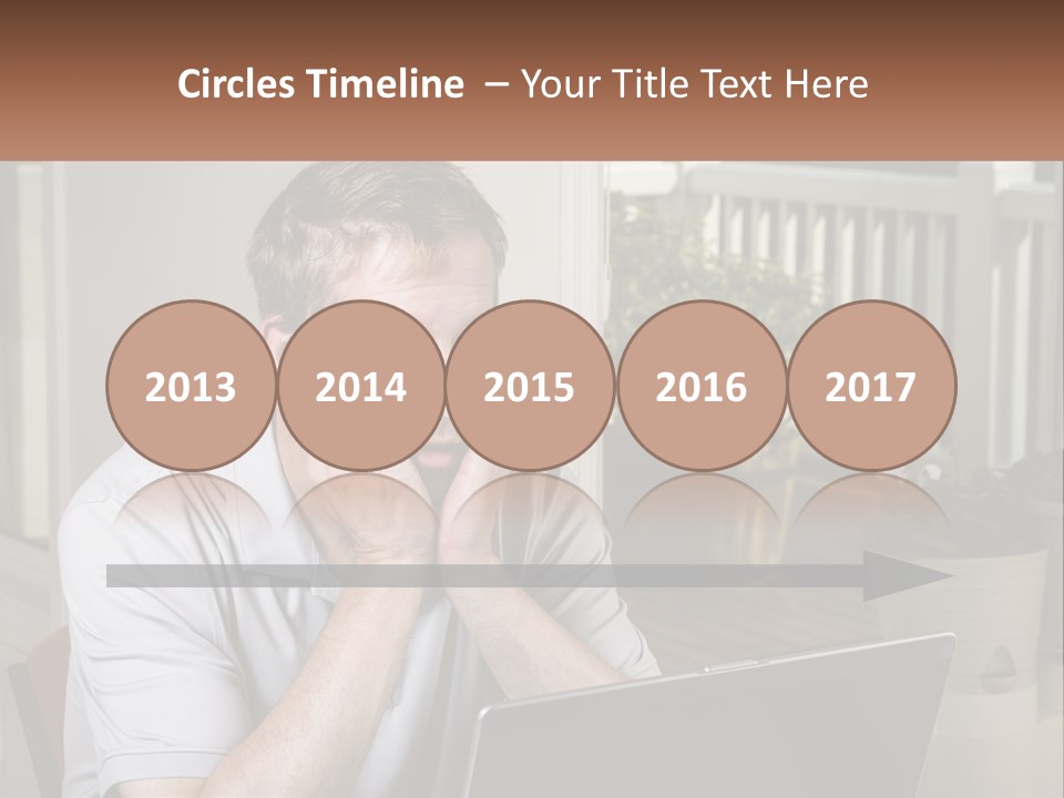 A Man Sitting At A Table With A Laptop In Front Of Him PowerPoint Template