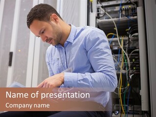 A Man Sitting In Front Of A Server In A Server Room PowerPoint Template