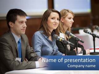 A Group Of People Sitting At A Table With Microphones PowerPoint Template