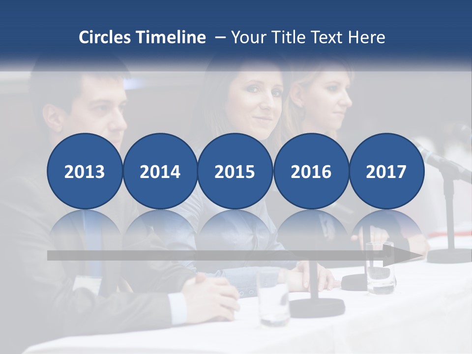 A Group Of People Sitting At A Table With Microphones PowerPoint Template