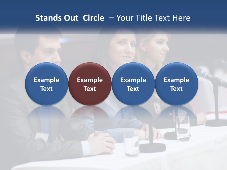 A Group Of People Sitting At A Table With Microphones PowerPoint Template