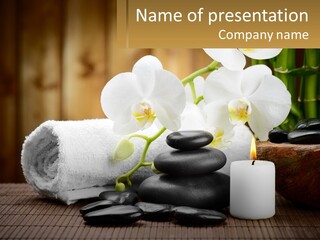 A White Candle And Some Black Rocks On A Table PowerPoint Template