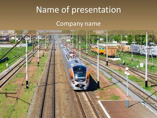 A Train Traveling Down Train Tracks Next To A Field PowerPoint Template