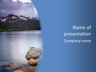 A Lake With Rocks In The Water And Mountains In The Background PowerPoint Template