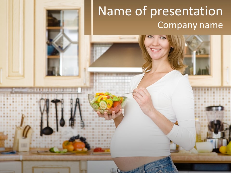 A Pregnant Woman Holding A Bowl Of Fruit In A Kitchen PowerPoint Template