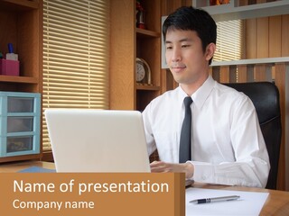 A Man Sitting At A Desk Using A Laptop Computer PowerPoint Template