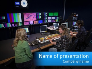 A Group Of People Sitting At A Desk With Computers PowerPoint Template