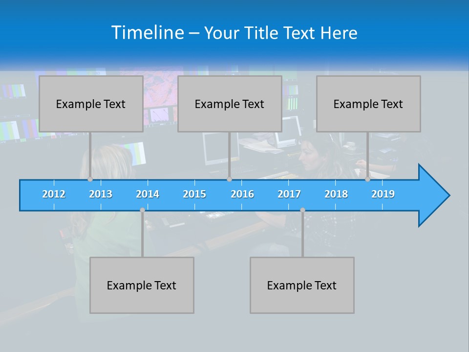 A Group Of People Sitting At A Desk With Computers PowerPoint Template