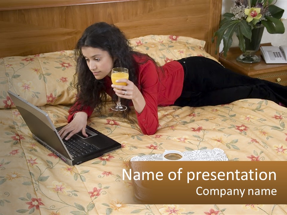 A Woman Laying On A Bed With A Laptop And A Glass Of Orange Juice PowerPoint Template