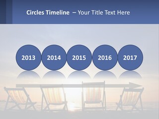 Two Chairs Sitting On A Beach With The Sun Setting In The Background PowerPoint Template