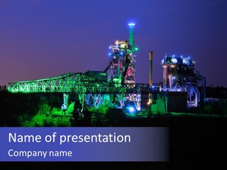 A Power Plant Lit Up At Night With Green And Blue Lights PowerPoint Template