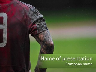 A Soccer Player Is Covered In Mud With A Green Field In The Background PowerPoint Template