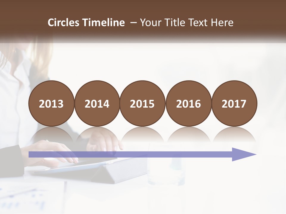 A Woman Sitting At A Table Using A Tablet Computer PowerPoint Template