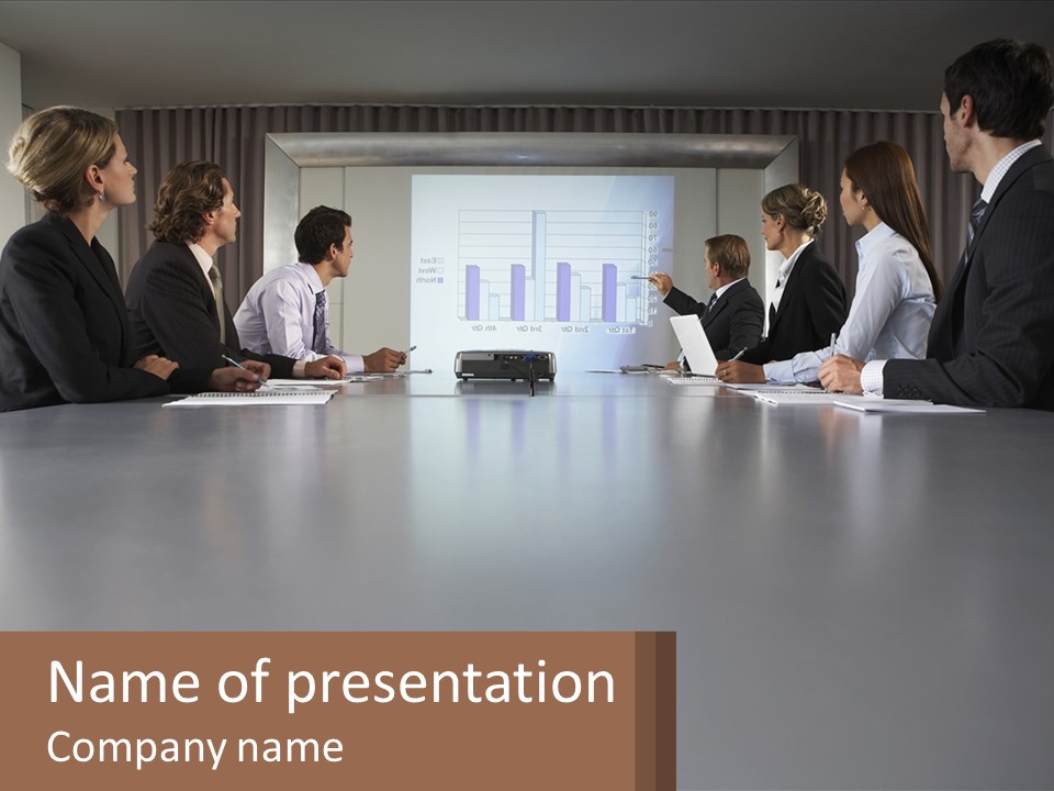 A Group Of People Sitting Around A Conference Table PowerPoint Template