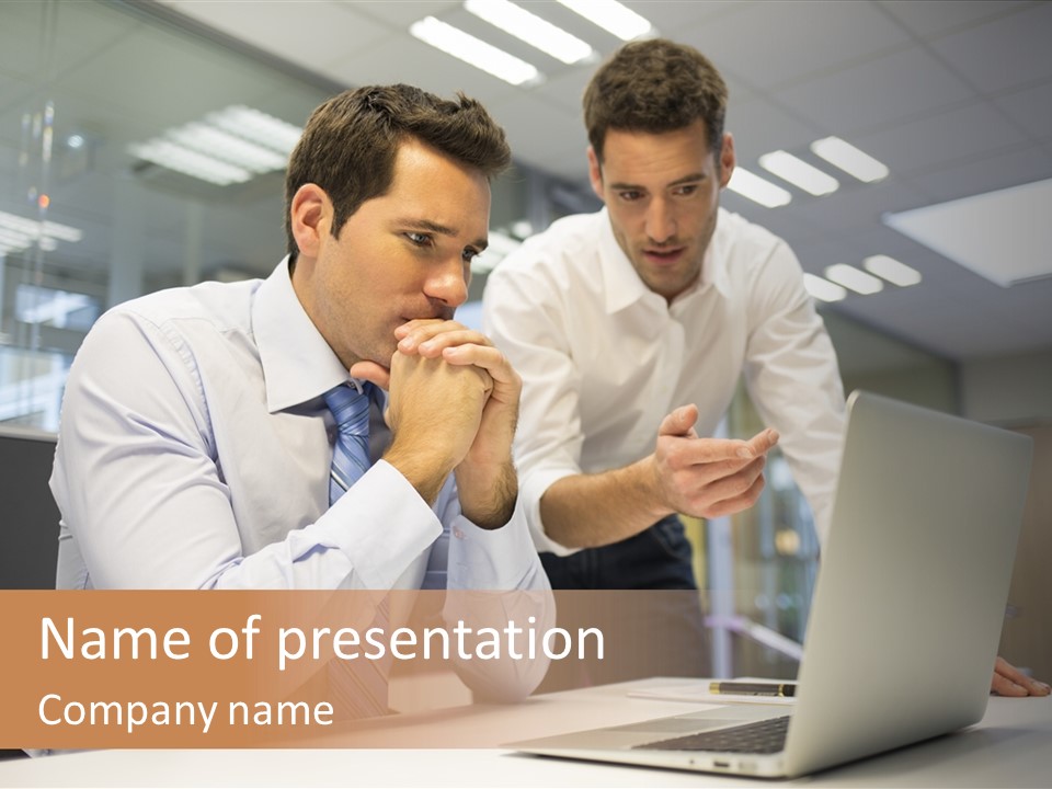 Two Men Sitting At A Table Looking At A Laptop PowerPoint Template