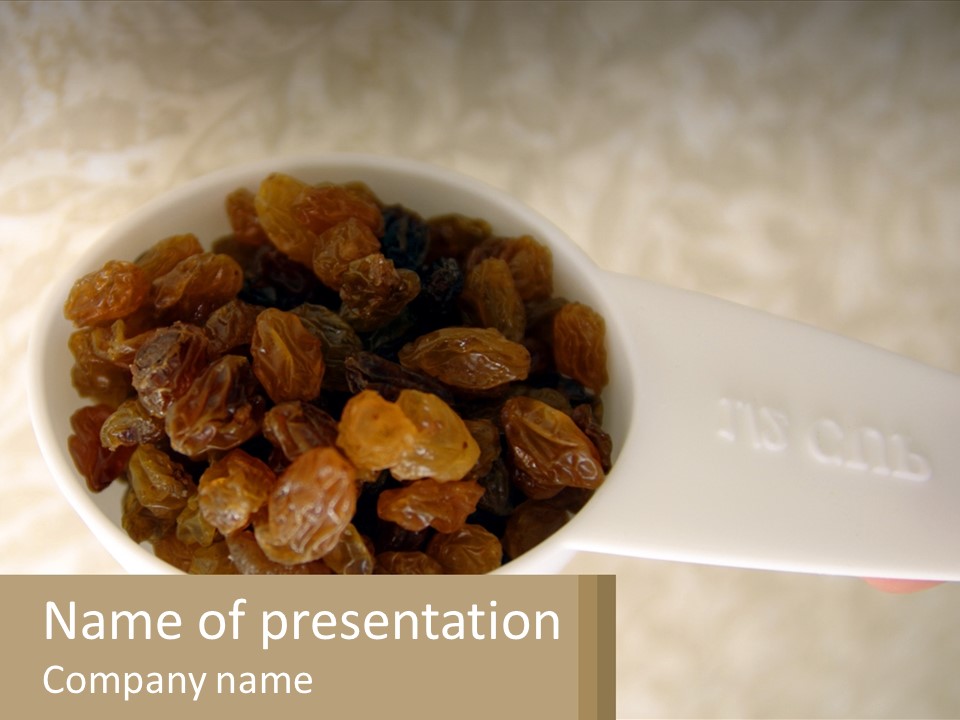 A White Spoon Filled With Raisins On Top Of A Table PowerPoint Template