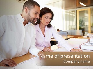 A Man And Woman Sitting At A Desk In An Office PowerPoint Template