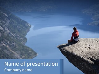 A Person Sitting On Top Of A Cliff Overlooking A Lake PowerPoint Template