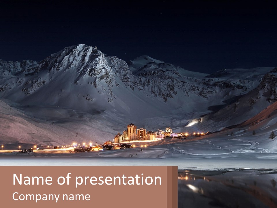 A Snowy Mountain With A Town Lit Up At Night PowerPoint Template