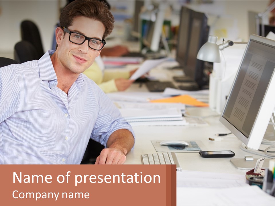A Man Sitting At A Desk In Front Of A Computer PowerPoint Template