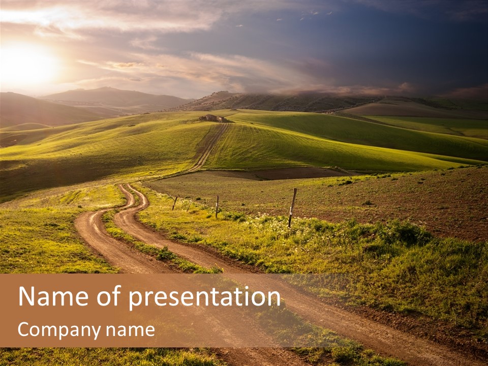 A Dirt Road In The Middle Of A Green Field PowerPoint Template