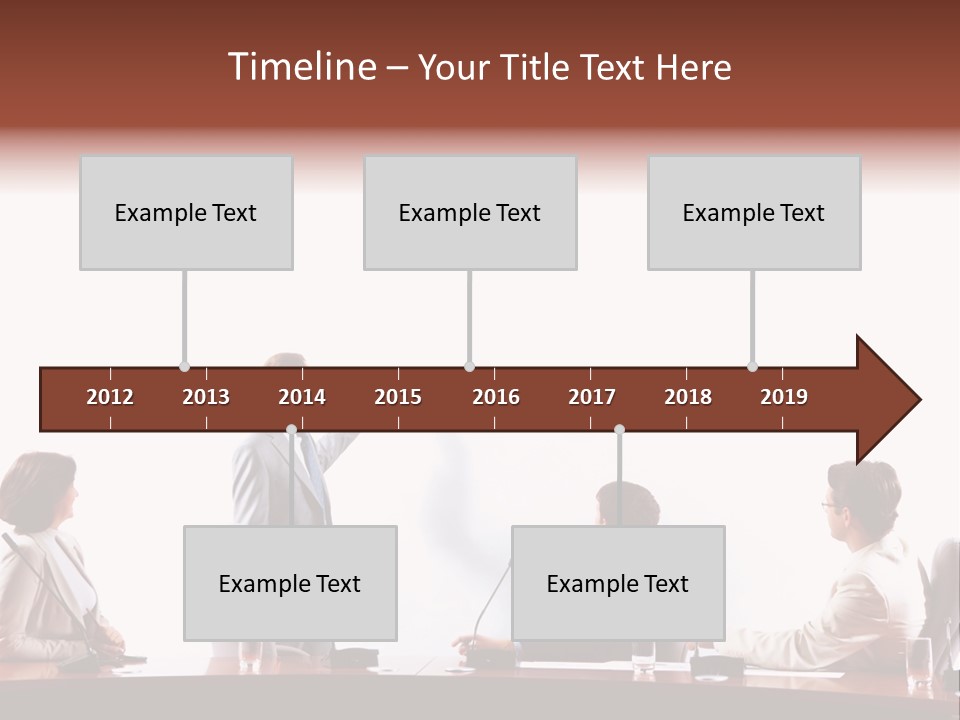 A Group Of People Sitting Around A Conference Table PowerPoint Template