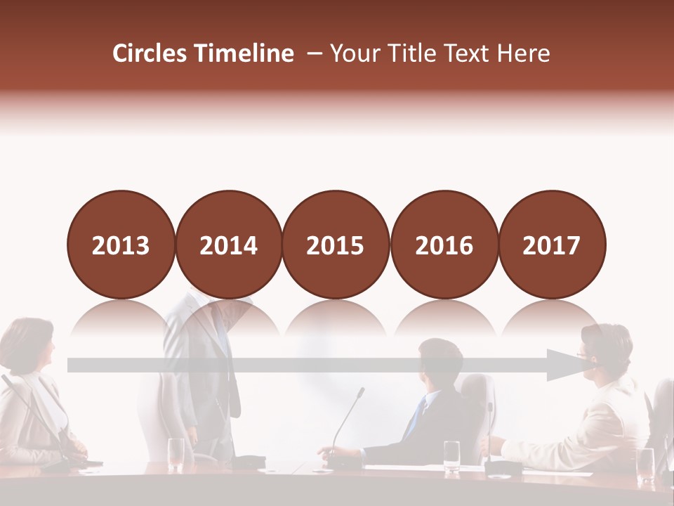 A Group Of People Sitting Around A Conference Table PowerPoint Template
