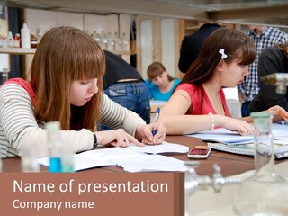 A Group Of People Sitting At A Table Writing PowerPoint Template