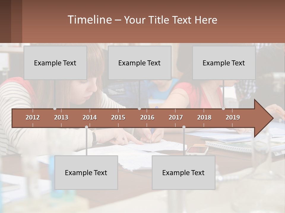 A Group Of People Sitting At A Table Writing PowerPoint Template