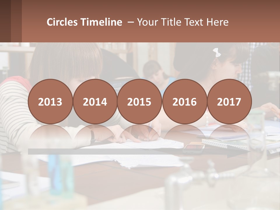 A Group Of People Sitting At A Table Writing PowerPoint Template