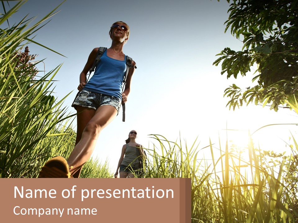 A Couple Of People Walking Through A Lush Green Field PowerPoint Template