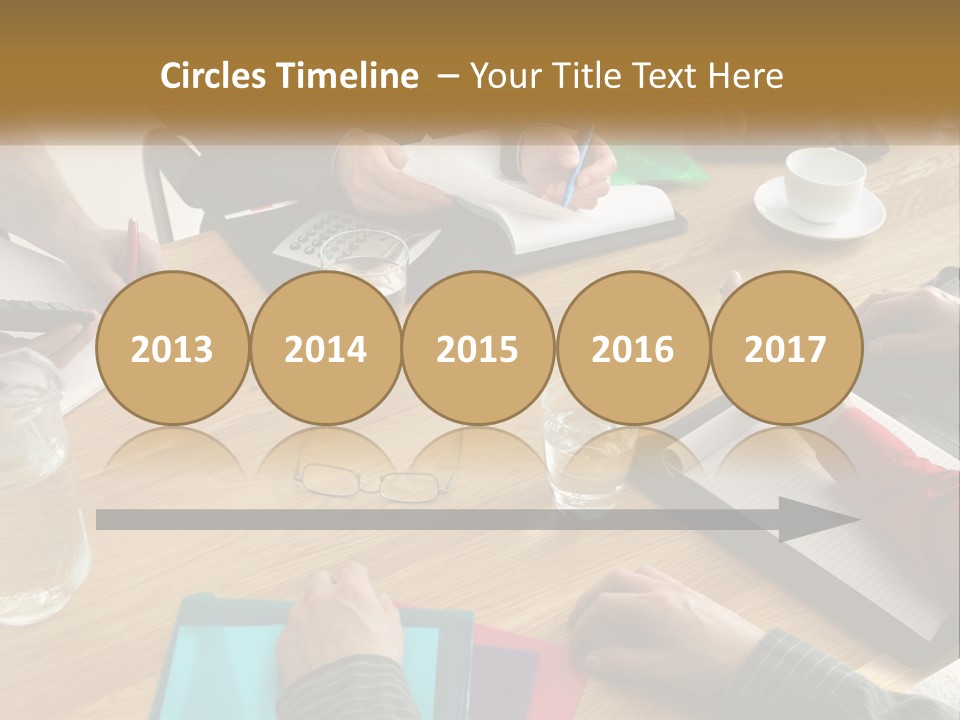 A Group Of People Sitting Around A Wooden Table PowerPoint Template